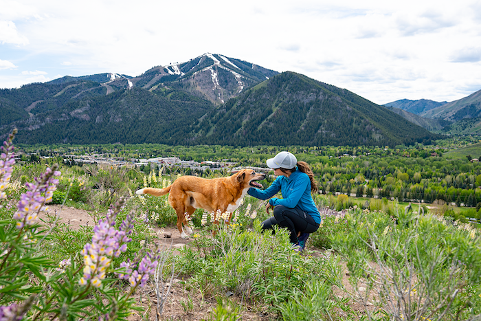 Woman runs through the wildflowers with a snow-capped Bald Mountain in the background